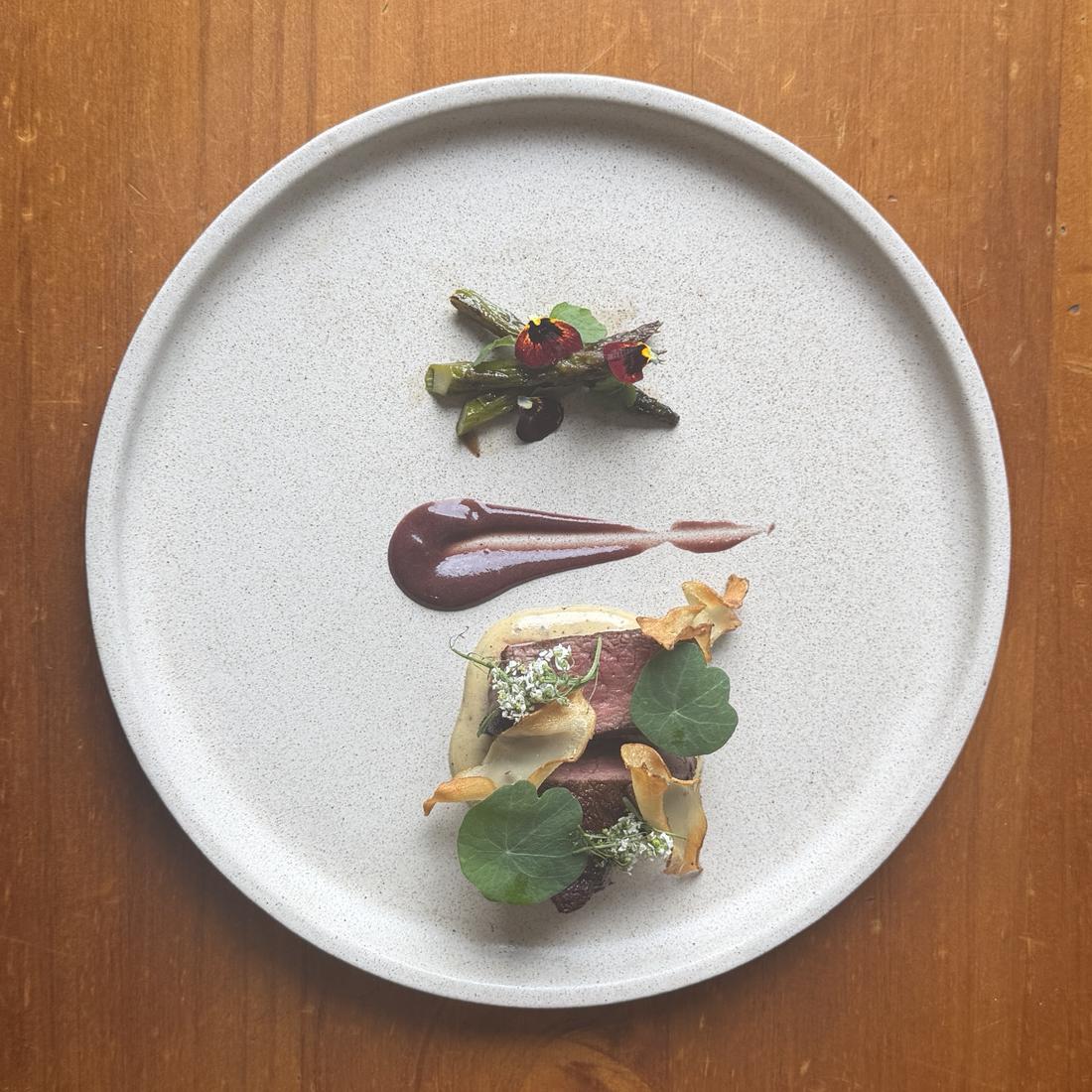 Plated fine-dining dish with asparagus and edible flowers