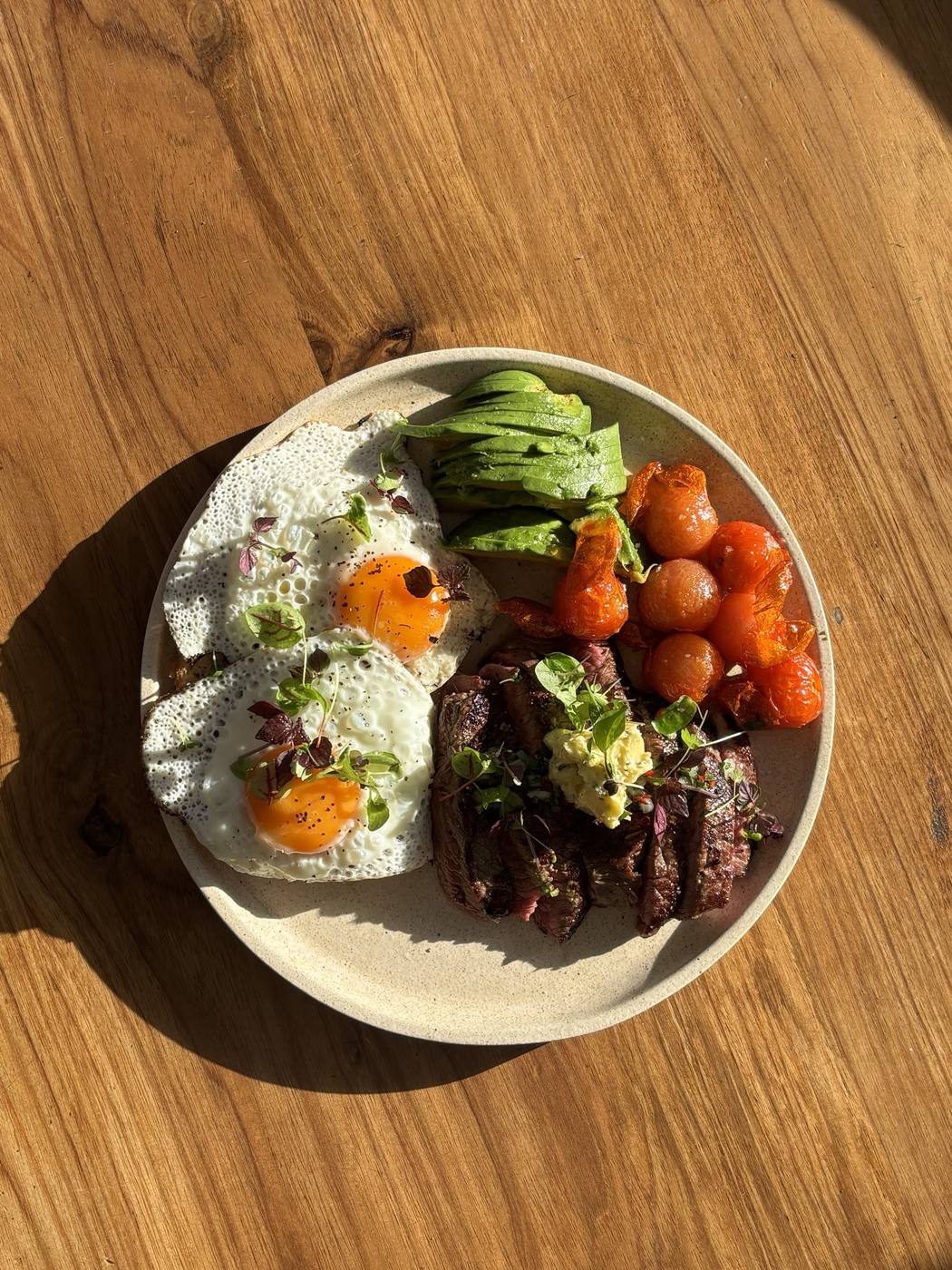 Steak and eggs breakfast plate with avocado and roasted tomatoes