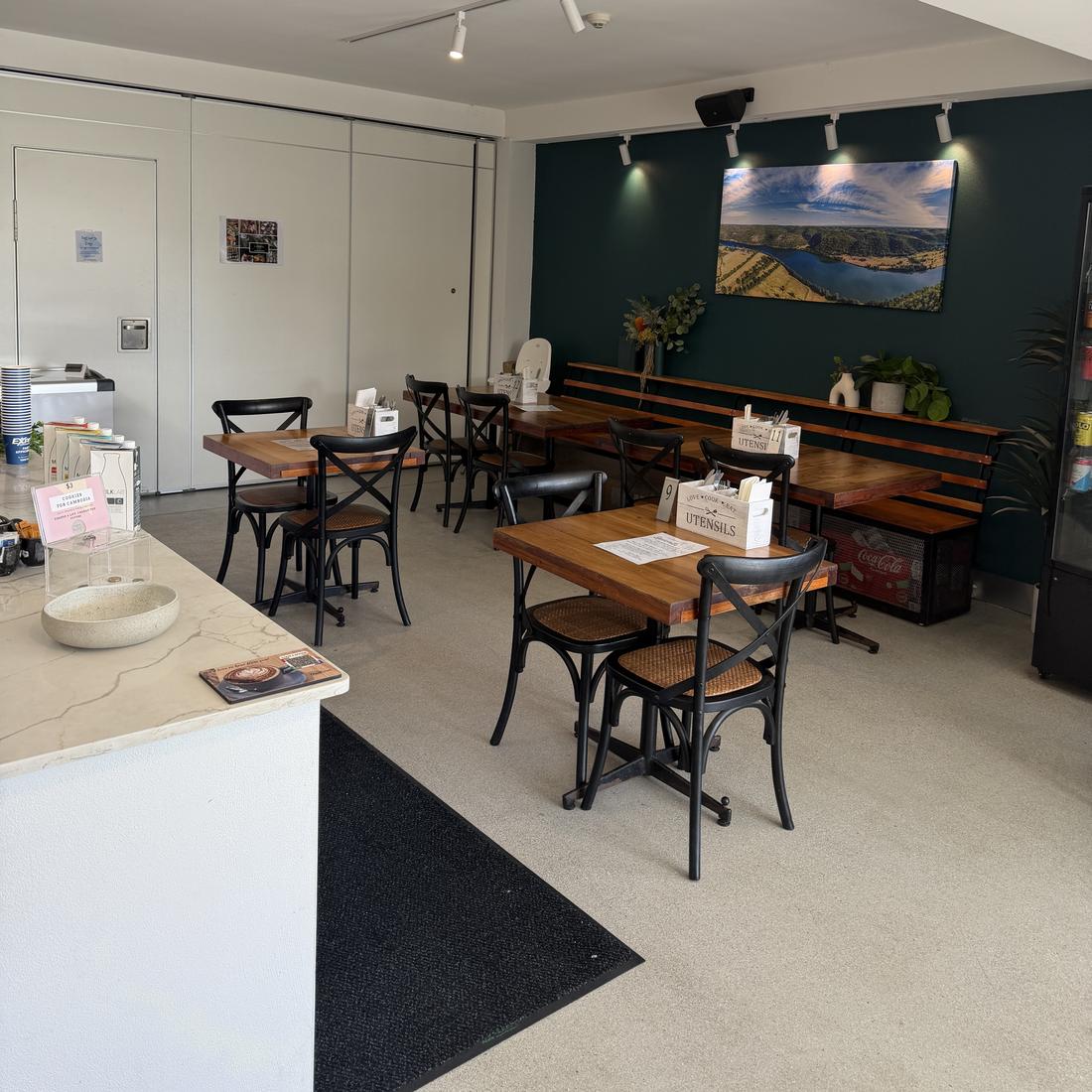 Cafe Cornerstone dining room with wooden tables and a teal feature wall